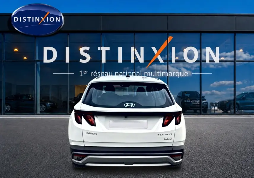 Vue arrière d’un Hyundai Tucson blanc hybride 2026, avec feux arrière sombres et logo Hyundai visible.