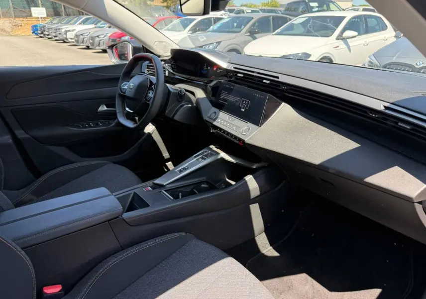 Vue intérieure côté conducteur de la Peugeot e-308 noire, avec tableau de bord digital et écran tactile central.