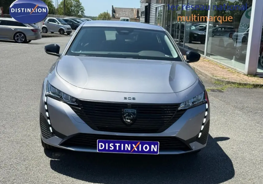 Vue avant frontale d'une Peugeot 308 e-308 2025 gris métallisé avec feux LED verticaux et calandre noire distinctive.