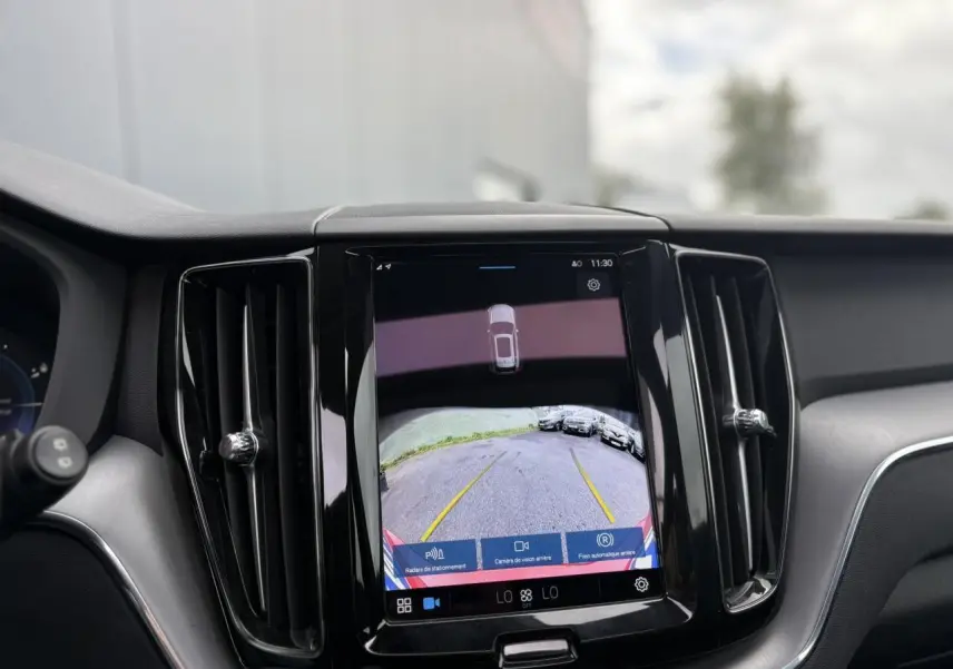 Écran tactile central affichant la caméra de recul du Volvo XC60 rouge fusion, intérieur noir avec aérateurs verticaux.