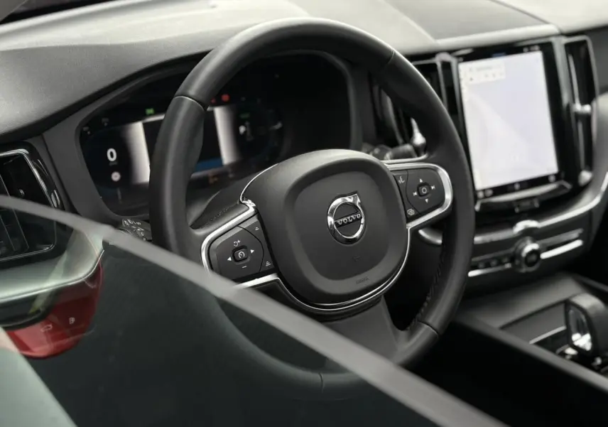 Vue rapprochée du volant noir multifonction et du tableau de bord digital du Volvo XC60 T6 AWD PHEV 2024.