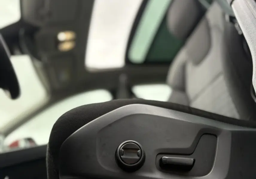 Gros plan sur les commandes électriques du siège avant d'un Volvo XC60 rouge Fusion 2024 avec toit ouvrant panoramique.