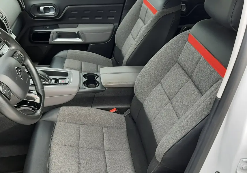 Vue intérieure côté conducteur de la Citroën C5 Aircross blanc, sièges gris avec bande rouge et tableau de bord moderne.