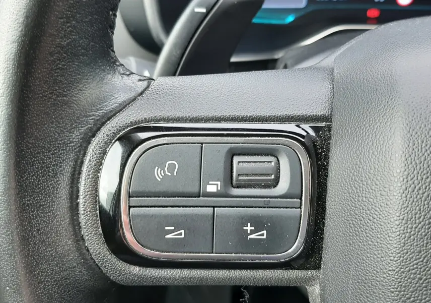 Gros plan sur les commandes de volume et téléphone au volant noir d'un Citroën C5 Aircross 2020, intérieur gris.
