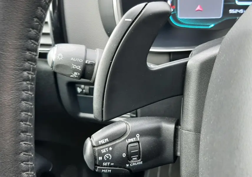 Gros plan sur les commandes au volant côté gauche du Citroën C5 Aircross blanc, avec levier de régulateur de vitesse et palettes de boîte auto.