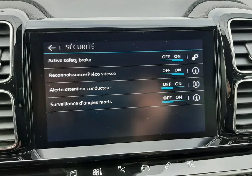 Vue rapprochée de l'écran tactile central du Citroën C5 Aircross blanc, affichant le menu sécurité avec options activées.