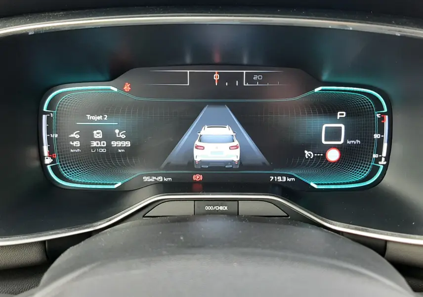 Vue rapprochée du tableau de bord numérique du Citroën C5 Aircross blanc, affichant la vitesse et l'assistance à la conduite.