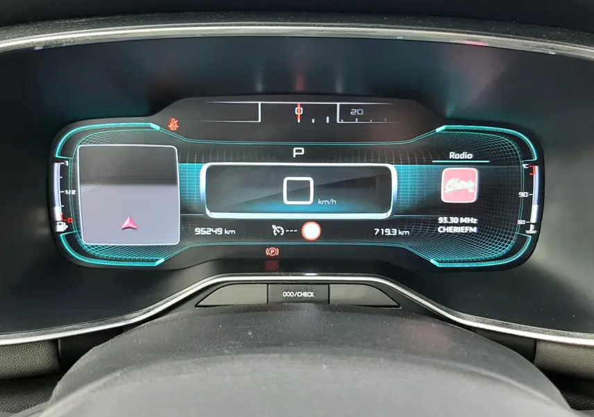 Vue rapprochée du tableau de bord numérique du Citroën C5 Aircross blanc, affichant la vitesse et la radio.