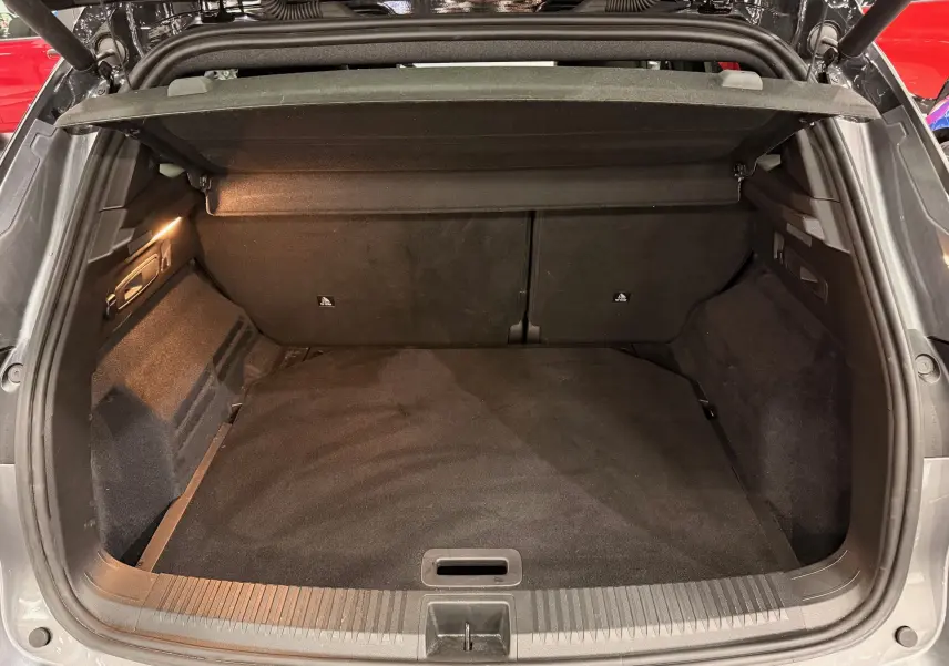 Coffre ouvert vu de l'arrière d'un Renault Austral gris schist avec intérieur noir et cache-bagages déployé.