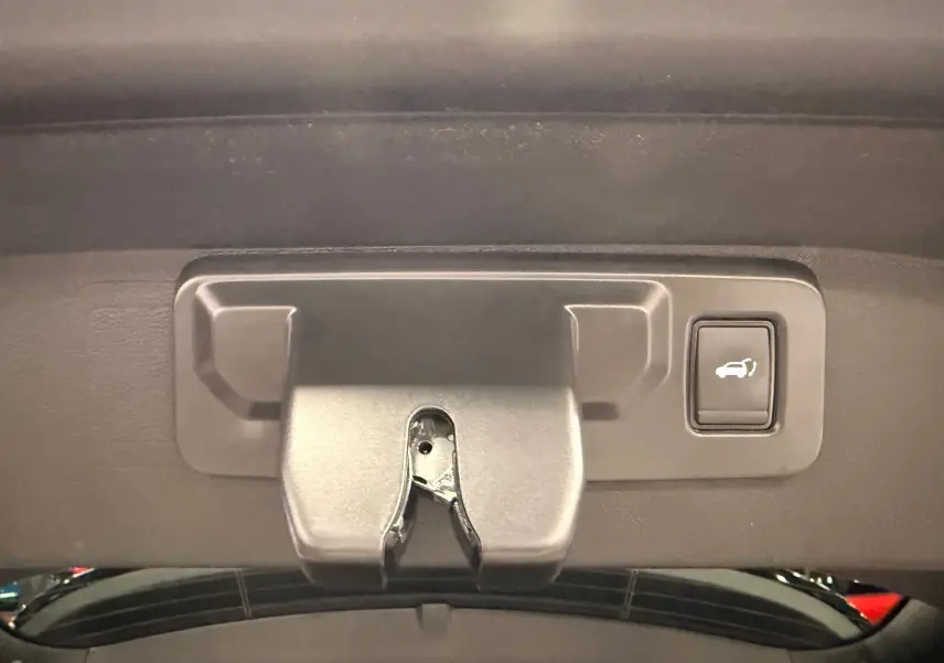 Gros plan sur la poignée intérieure et le bouton d'ouverture du coffre du Renault Austral gris schist avec toit noir.