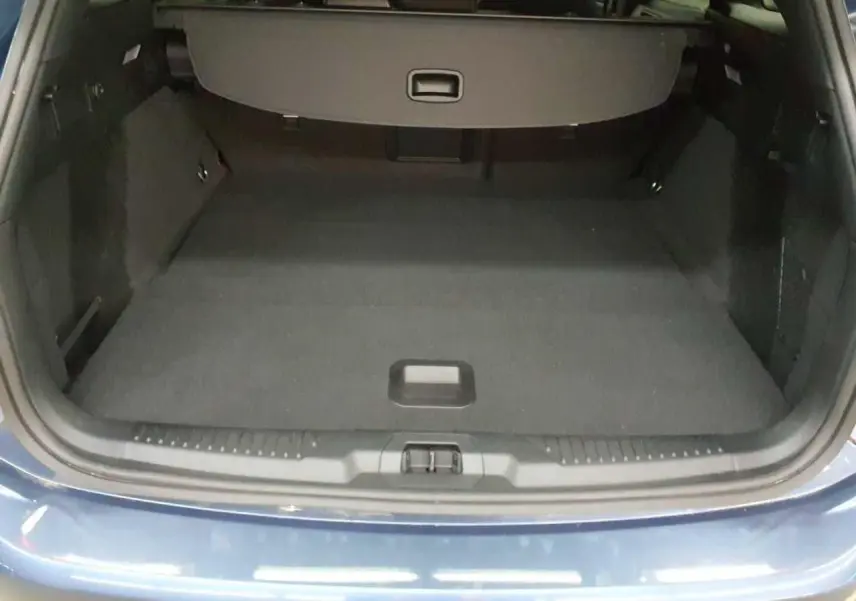 Vue du coffre ouvert d'une Ford Focus SW 2023 Bleu Azur, montrant l'espace de chargement vide et la finition intérieure noire.