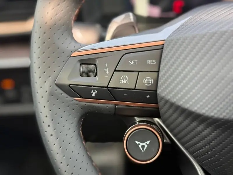 Gros plan sur les commandes à gauche du volant perforé avec insert cuivre du CUPRA Formentor Gris Graphène 2026.