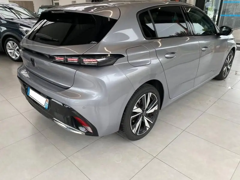 Vue 3/4 arrière droit d'une Peugeot 308 2022 gris Artense avec feux arrière LED et jantes alliage distinctives.