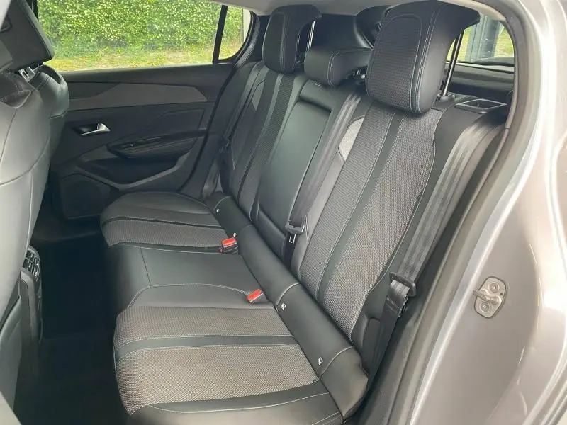 Vue latérale droite de l'intérieur arrière de la Peugeot 308 gris Artense, montrant les sièges en tissu et cuir noir.