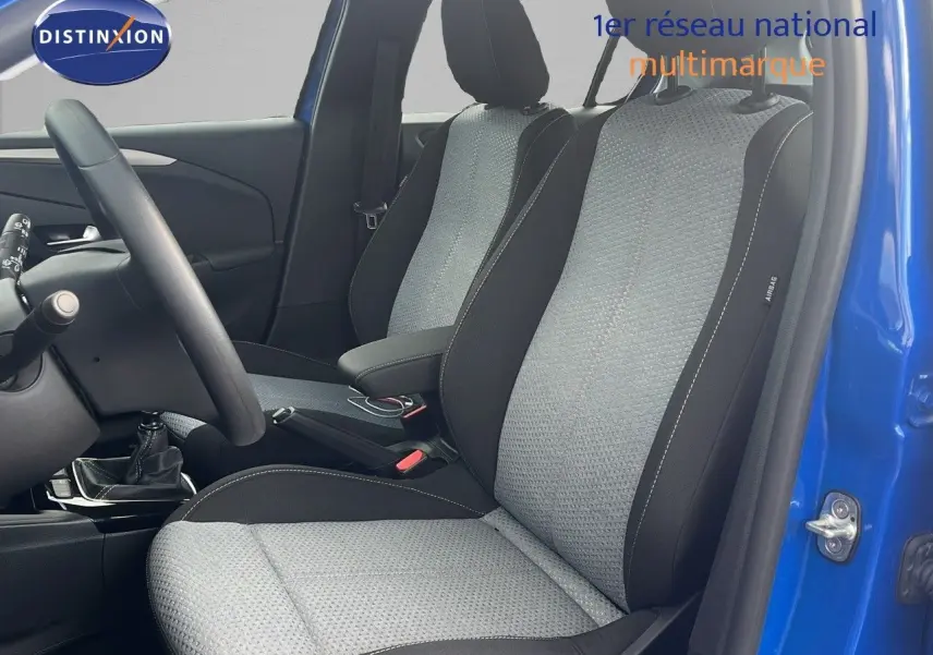 Intérieur avant de l'Opel Corsa 2025 bleu voltaik, sièges tissu gris noir et volant côté gauche visible.