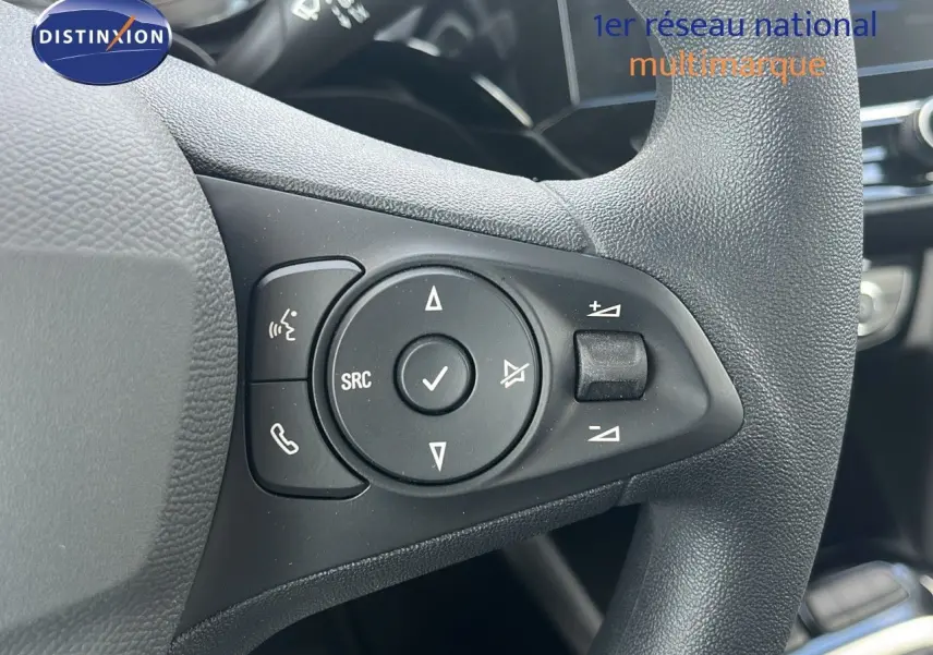 Gros plan sur les commandes multifonctions au volant d'une Opel Corsa 2025, finition Bleu Voltaik Metal.