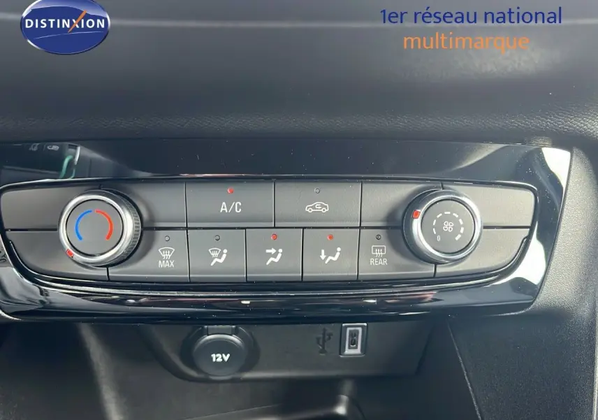 Tableau de bord de l'Opel Corsa bleu voltaik métal 2025 montrant les commandes de climatisation et prise 12V.