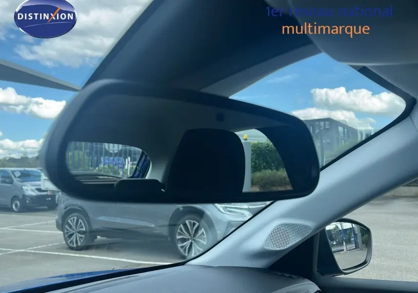 Intérieur de l’Opel Corsa bleu voltaik métal 2025 vu côté conducteur avec rétroviseur et vitre latérale visibles.