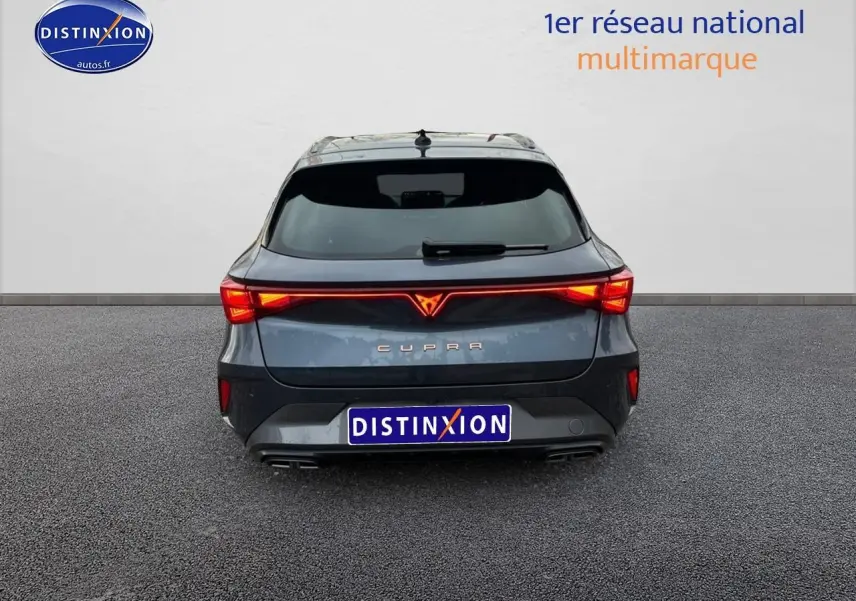 Vue arrière d'une CUPRA Leon ST gris magnétique avec feux LED allumés et double sortie d'échappement.