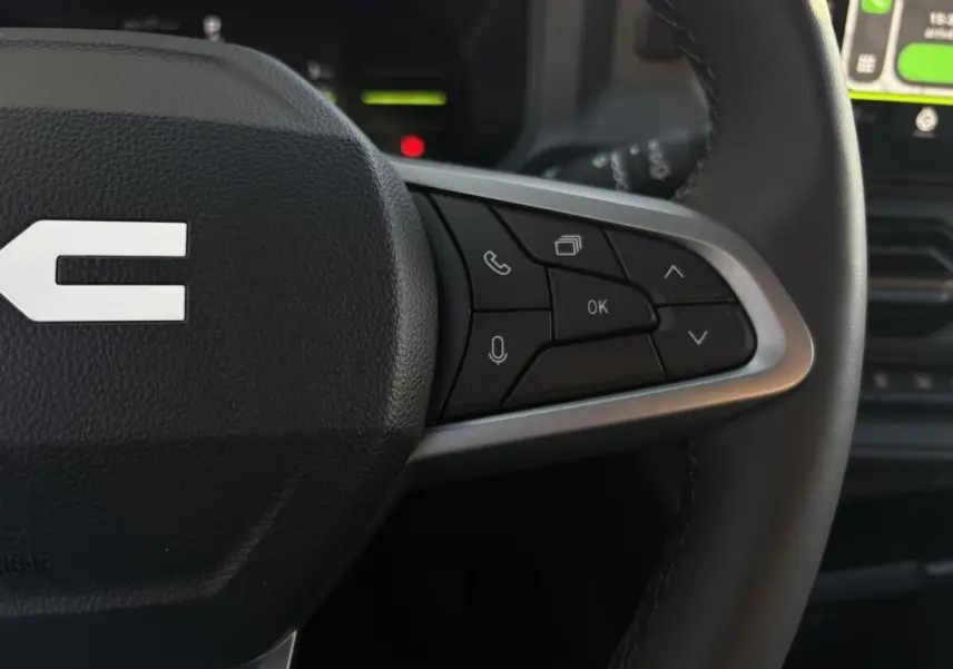 Gros plan sur les commandes au volant côté droit du Dacia Duster 2026, volant en cuir avec touches multifonctions.