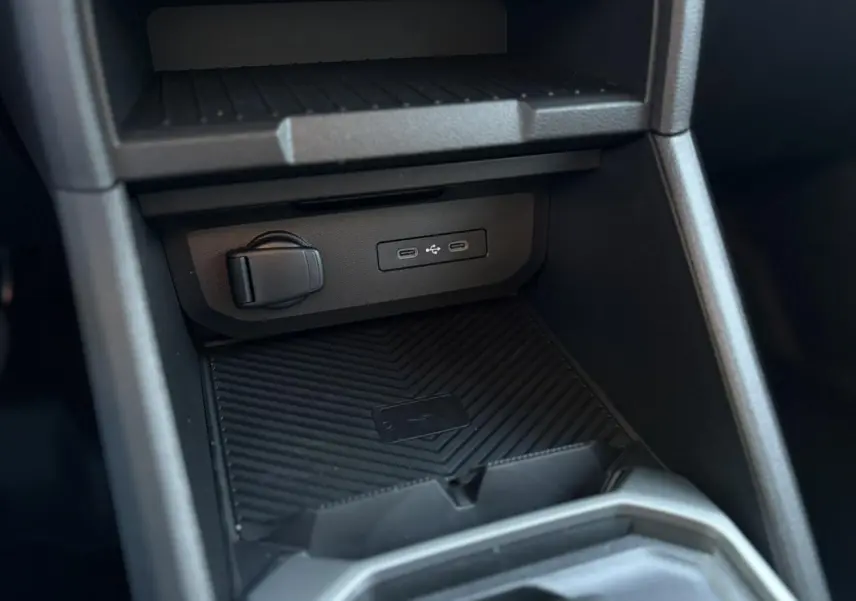 Détail de la console centrale du Dacia Duster 2026, zone de charge à induction avec ports USB et prise 12V.