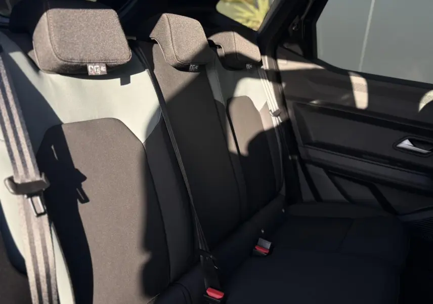 Vue latérale droite de la banquette arrière noire et grise du Dacia Duster 2026 avec ceintures de sécurité et appuie-têtes.
