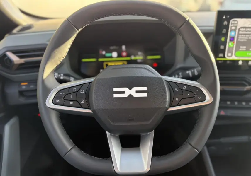 Gros plan sur le volant noir du Dacia Duster 2026 avec commandes intégrées et tableau de bord digital en arrière-plan.