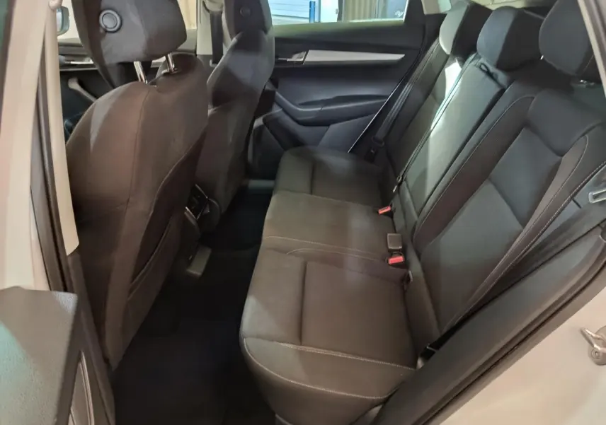 Vue intérieure côté droit montrant la banquette arrière noire du Skoda Karoq blanc 2024 avec sièges en tissu.