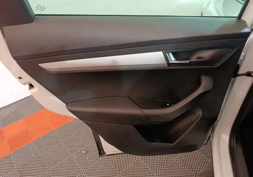 Vue côté gauche de la porte avant blanche du Skoda Karoq 2024, avec garniture noire et insert argenté.