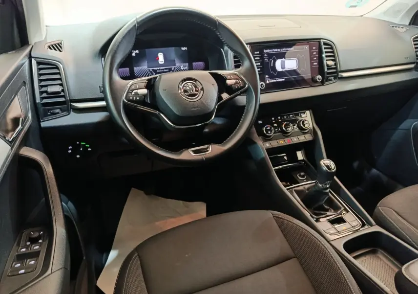 Intérieur noir du Skoda Karoq 2024 vu de face, avec volant cuir multifonctions et écran tactile central.