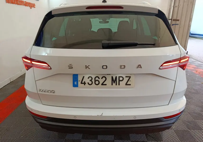 Vue arrière d'un Skoda Karoq blanc 2024 avec feux LED allumés et plaque d'immatriculation espagnole visible