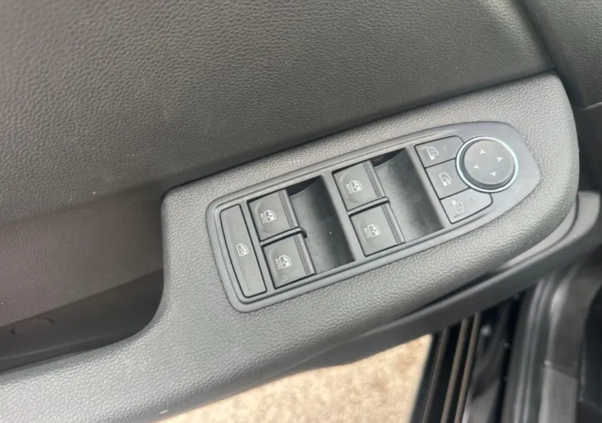 Gros plan sur les commandes des vitres électriques et réglages des rétroviseurs côté conducteur de la Renault Clio noire 2025.