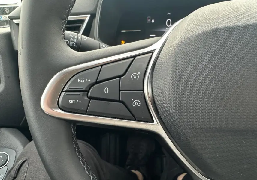 Gros plan sur les commandes du régulateur de vitesse au volant noir de la Renault Clio V dCi 100 Evolution 2025.