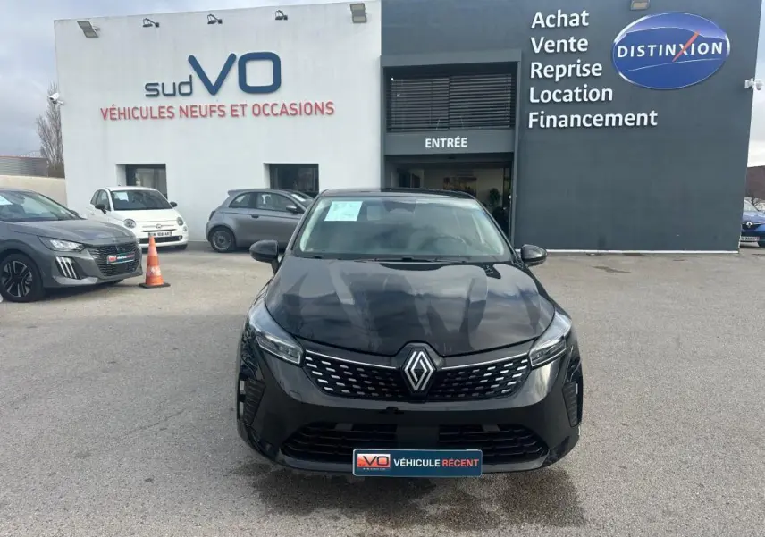 Vue avant d'une Renault Clio V dCi 100 Evolution noire stationnée devant un concessionnaire avec calandre distinctive.