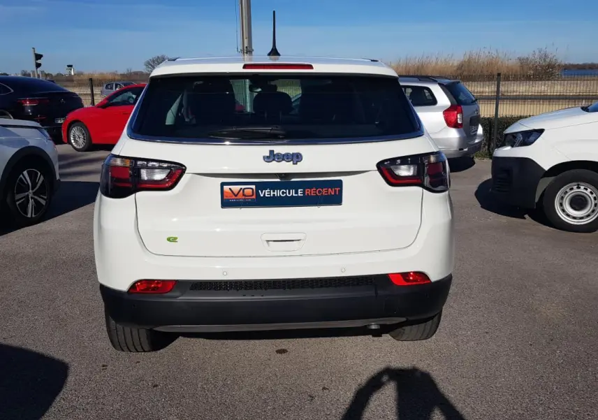 Vue arrière d'un Jeep Compass blanc 2024 avec feux LED et logo Jeep visible sur un parking extérieur.
