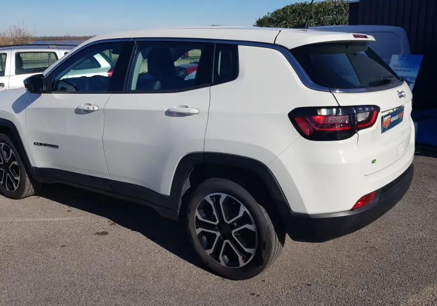 Vue 3/4 arrière gauche d'un Jeep Compass blanc 2024 avec jantes alliage 18 pouces et feux arrière LED.