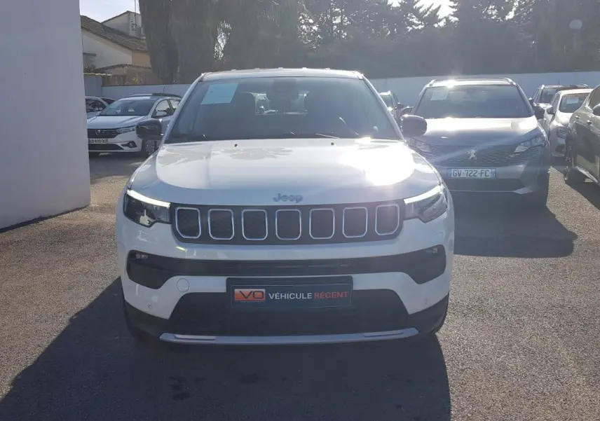 Vue frontale d'un Jeep Compass blanc 2024 avec calandre à sept fentes et phares LED allumés.