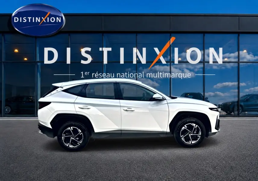 Profil droit du Hyundai Tucson blanc 2026 avec jantes alliage 17 pouces, devant une vitrine Distinxion.