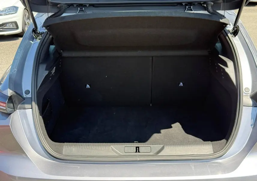 Coffre ouvert vu de l'arrière d'une Peugeot 308 e-308 gris Artense, montrant l'espace de chargement vide.