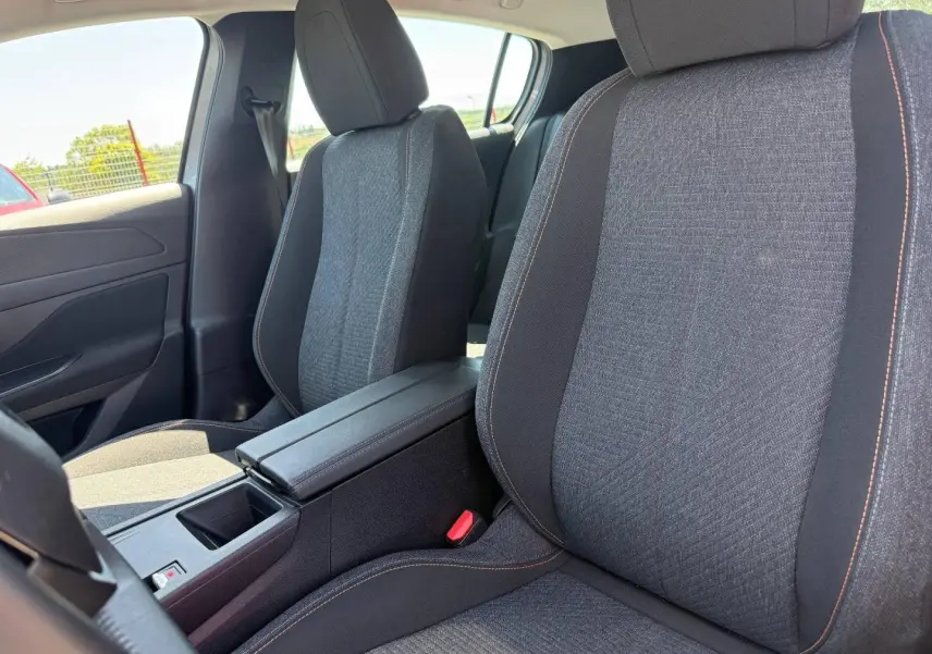 Vue intérieure rapprochée des sièges avant gris tissu avec accoudoir central de la Peugeot 308 e-308 2025.
