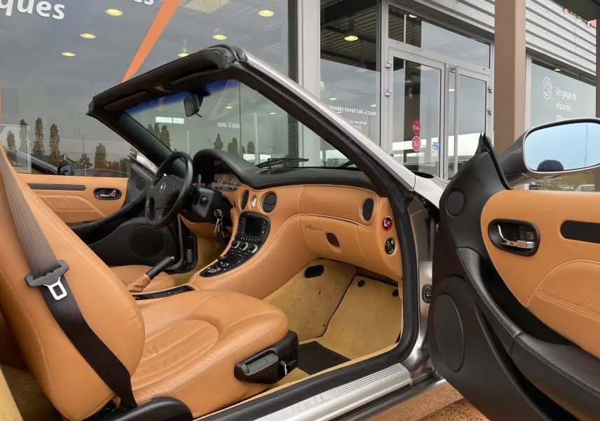 Intérieur cuir beige clair d'une Maserati Spyder gris Nuvolari, vue côté conducteur avec tableau de bord et console centrale visibles.