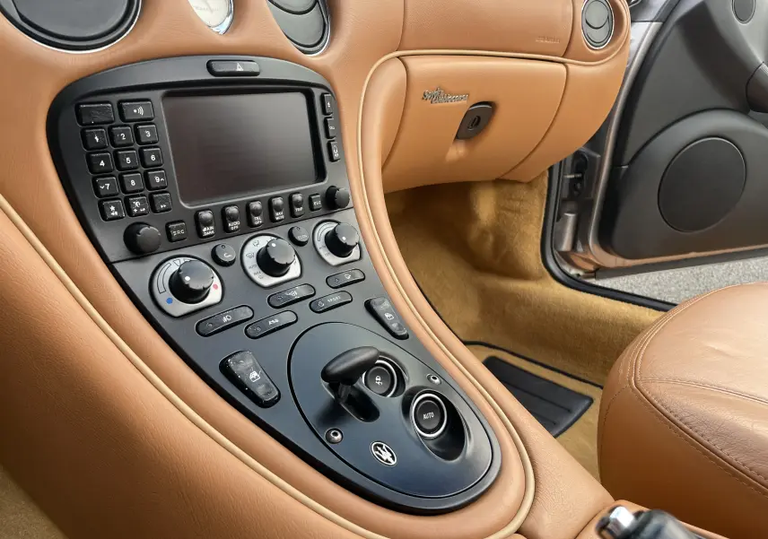Vue rapprochée de la console centrale en cuir beige de la Maserati Spyder 2002 avec commandes et levier de boîte automatique.
