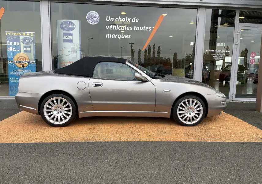 Profil côté gauche d'une Maserati Spyder gris Nuvolari 2002 avec capote noire, jantes alliage et ligne élégante sportive.