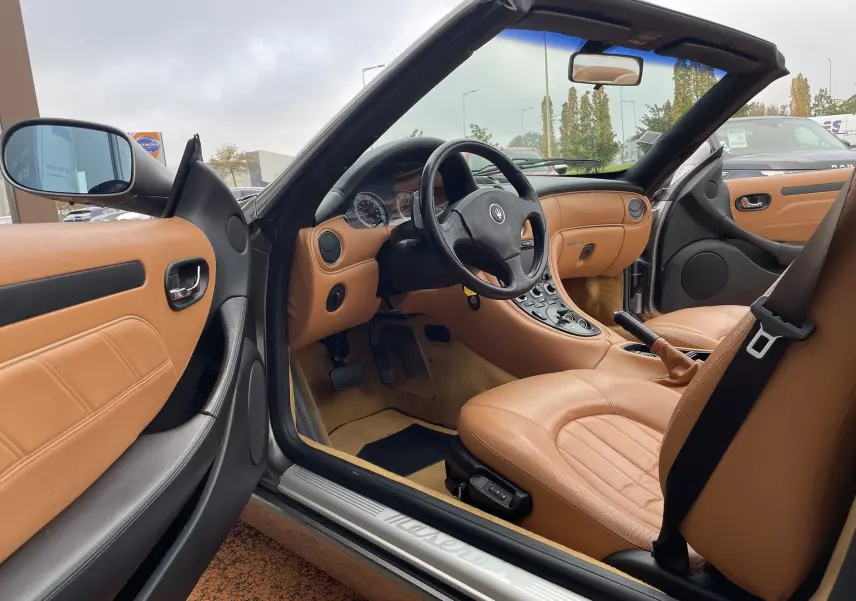 Intérieur cuir beige vu côté conducteur d'une Maserati Spyder gris Nuvolari cabriolet, tableau de bord et volant visibles.