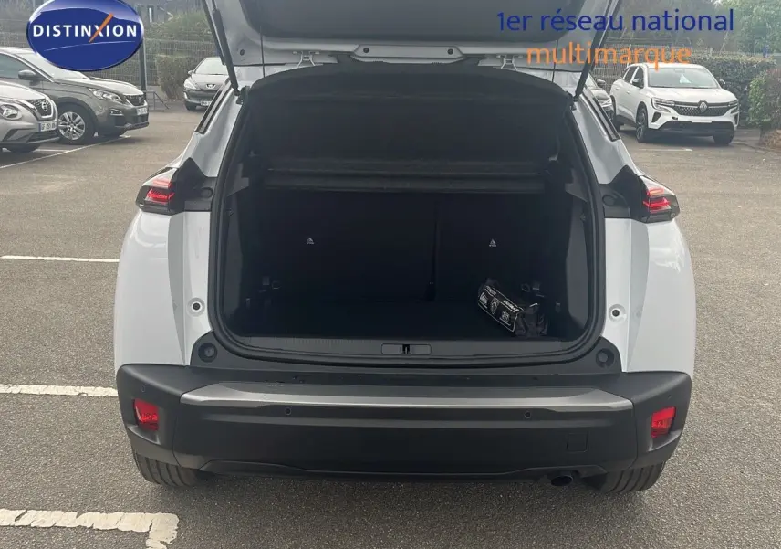 Vue arrière d'un Peugeot 2008 blanc Okenite Metal 2025 avec coffre ouvert et sac de secours visible.