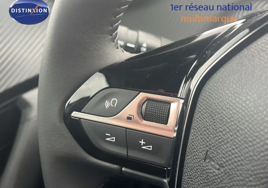 Gros plan sur les commandes de volume et téléphone du volant cuir noir d'une Peugeot 2008 blanche 2025.