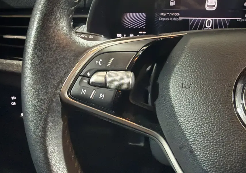 Gros plan sur la partie gauche du volant cuir du Skoda Kamiq rouge 2024 avec commandes multimédia intégrées.