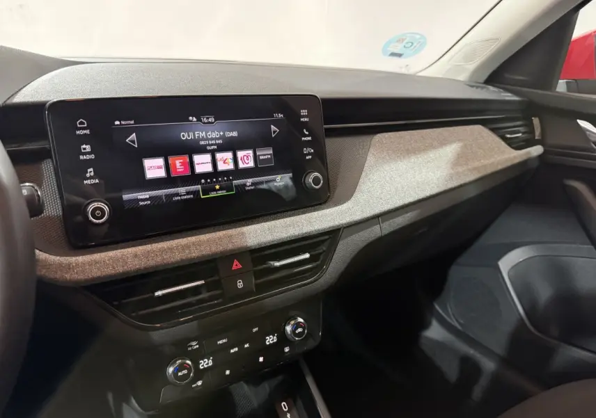 Intérieur du Skoda Kamiq 2024, vue du tableau de bord avec écran tactile central et finition tissu gris clair.