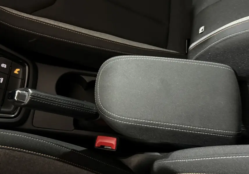 Vue rapprochée de la console centrale noire avec frein à main manuel et accoudoir du Skoda Kamiq 2024.