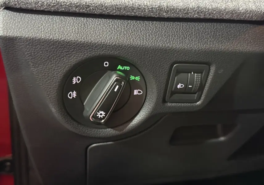Gros plan sur le bouton de commande des phares avec réglage automatique sur Skoda Kamiq rouge 2024.